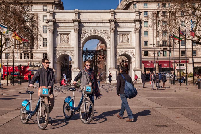 Marble Arch, London, England. Tourists walk  with hired cycles.