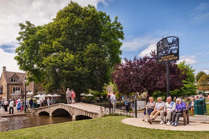 Tourists enjoy summer afternoon in the Cotswold village of Bourton-on-the-Water, Gloucestershire, England.