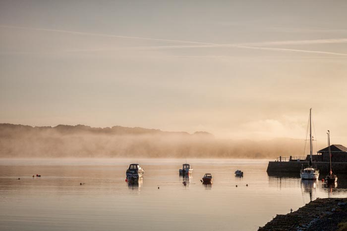 Boats moored on a misty morning in the harbour of the fishing village of Garlieston in Wigtownshire, Dumfries and Galloway, Scotland.