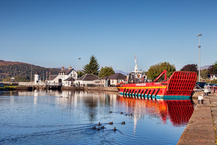 The Lock-Keepers house, the Lighthouse at Corpach, and the Ferguson general duty ship Carhie Anne at the final lock on the Caledonian Canal, Highland, Scotland, UK