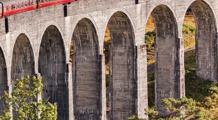 The Jacobite steam train blows steam from the exhaust as it crosses the Glenfinnan Viaduct, Highland, Scotland, UK.