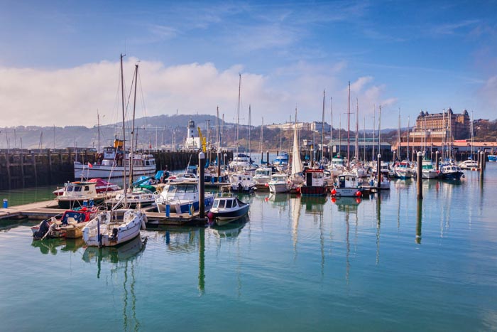Scarborough Harbour, with the Grand Hotel and Oliver's Mount in the distance, North Yorkshire, England, UK