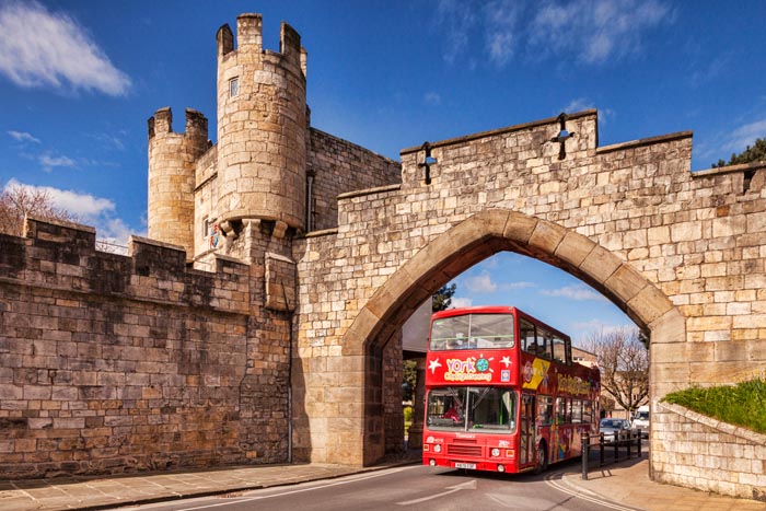 Tour bus driving through Walmgate Bar, York, North Yorkshire, England, UK