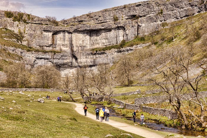 Hikers on the Pennine Way, walking towards Malham Cove, Yorkshire Dales National Park, North Yorkshire, England, UK