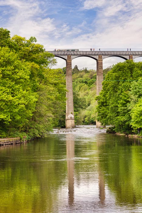 Pontcysyllte Aqueduct, built by Thomas Telford, and a World Heritage Site, reflecting in the River Dee, with a narrowboat and people walking across, near Llangollen, County Borough of Wrexham, Wales, UK