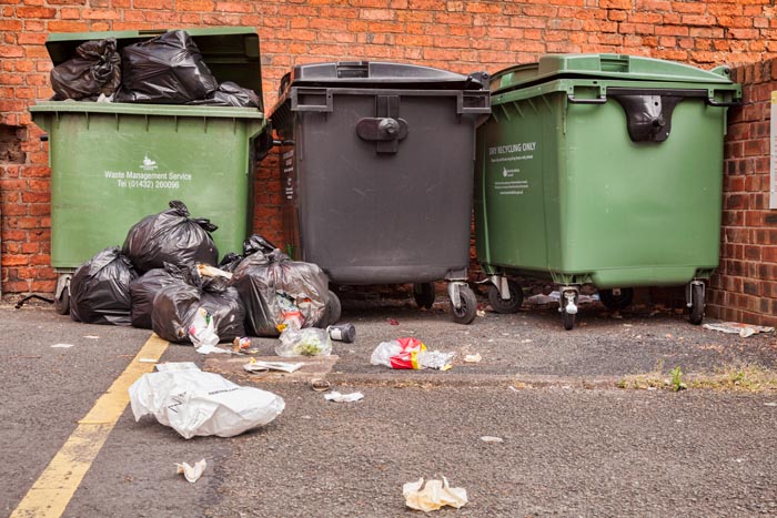Overflowing commercial dustbins on the street in Hereford, Herefordshire, England, UK