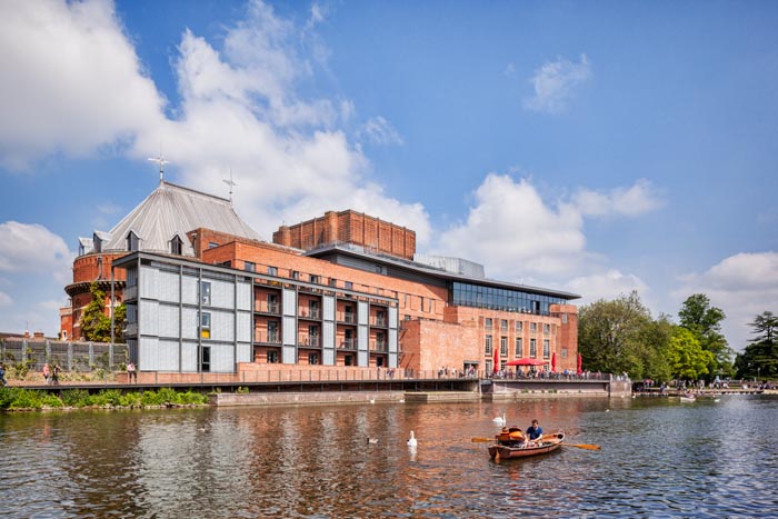 Royal Shakespeare Theatre and the River Avon and people in boats on the river on a sunny weekend in late spring, Stratford-upon-Avon, Warwickshire, England, UK