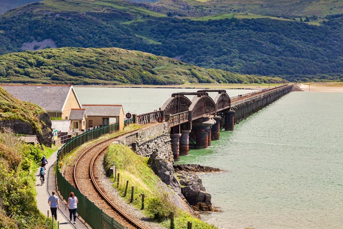 Couple and cyclists approaching the walkway across the Barmouth Viaduct, Gwynedd, Wales, UK