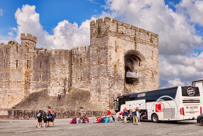 Tourists and tour coach at Caernarfon Castle, Gwynedd, Wales, UK