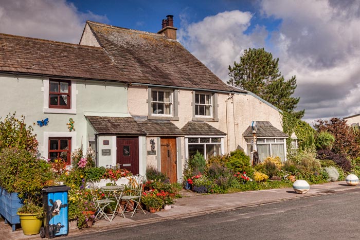 Cottages with lovely summer gardens and a decorated dustbin in Main Street, Ravenglass, Cumbria, England, UK