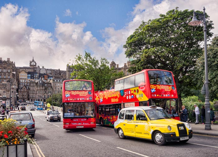 Sightseeing buses and a yellow taxi on Waverley Bridge, Edinburgh, with a view to the Old Town, Edinburgh, Scotland, UK