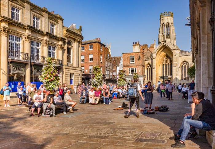 Crowds watching one man band busking in St Helen's Square, York, North Yorkshire, England, UK